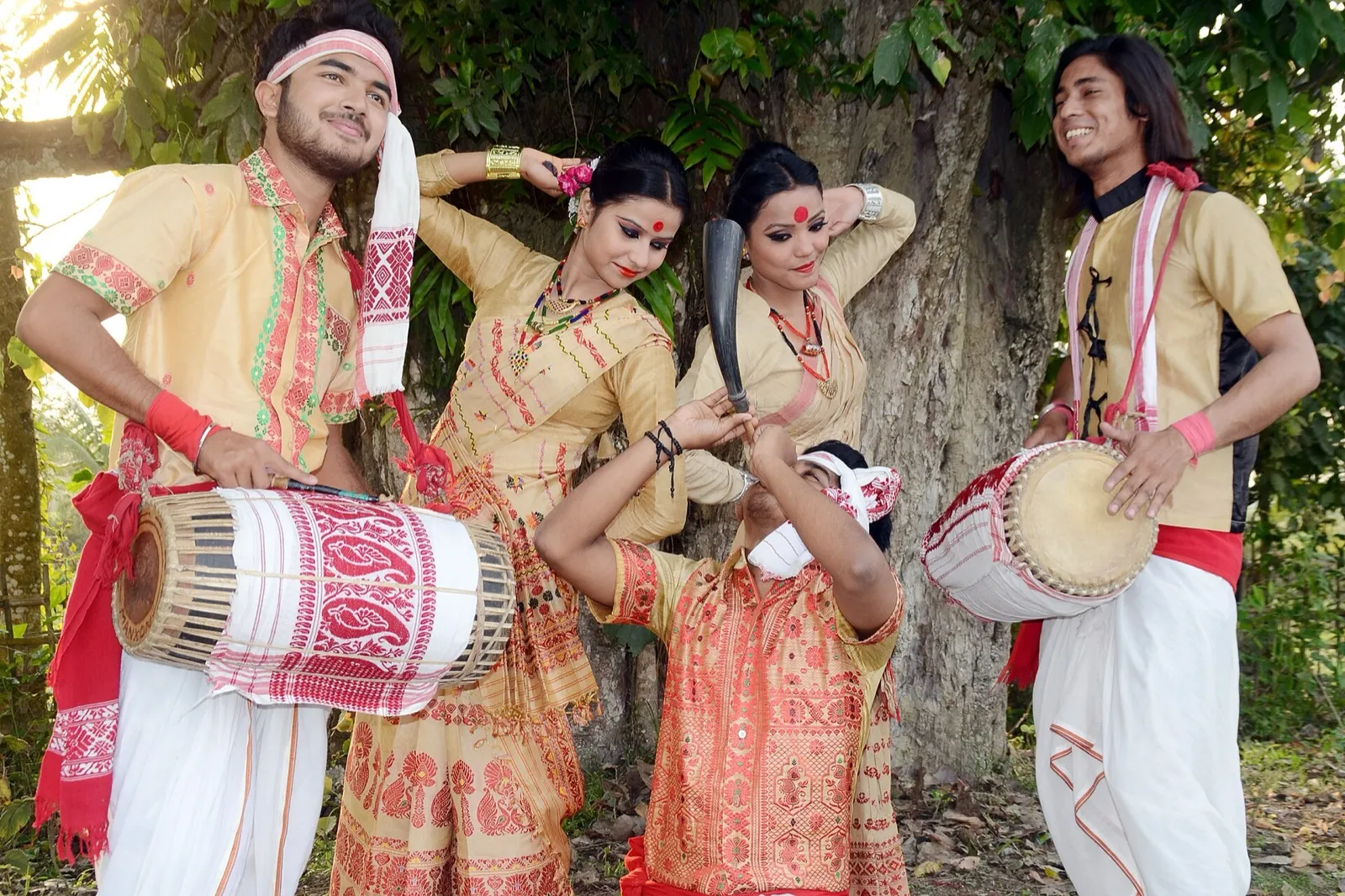 Young men and women in traditional dress performing Bihu with dhol drums
